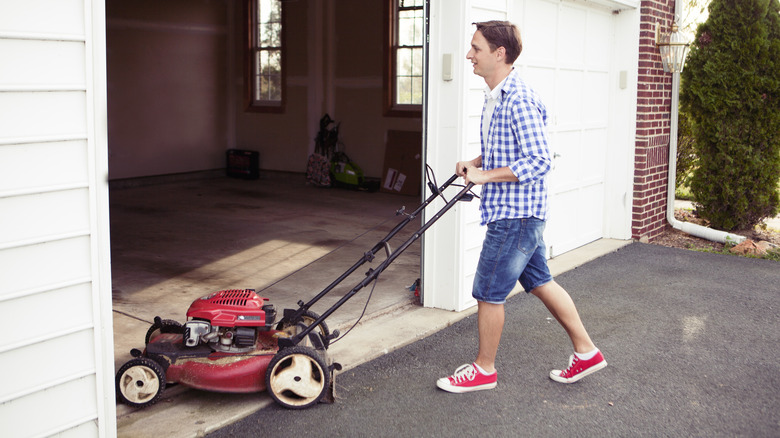 Man pushing mower into garage