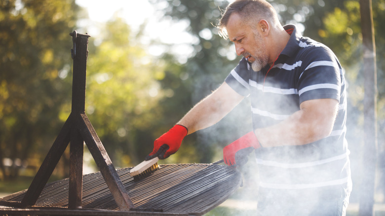 man cleaning barbecue grill racks