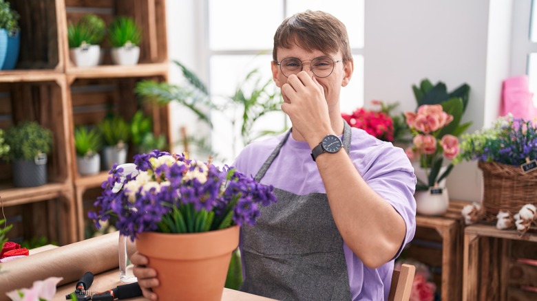Man holding nose in flower shop