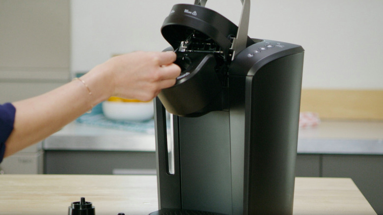 person cleaning keurig machine