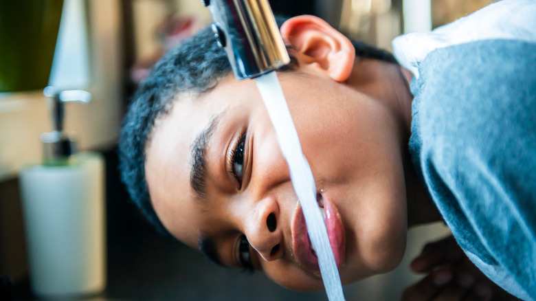 boy drinking from faucet