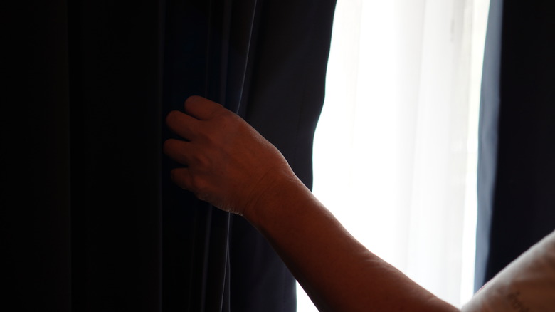 person opening a blackout curtain