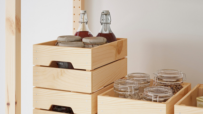 A wooden IKEA crate on pantry shelf holding bottles and jars of food