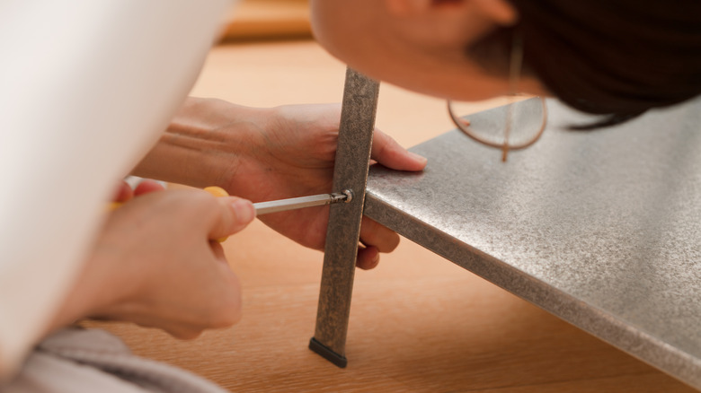 Someone building a metal piece of furniture