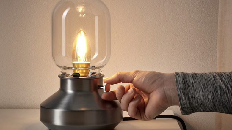 Person's hand turning TÄRNABY lamp's knob to dim light