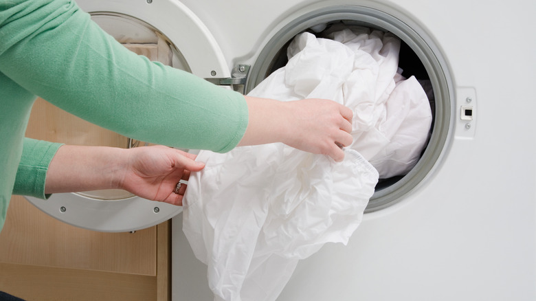 Hands taking bedsheets from washer