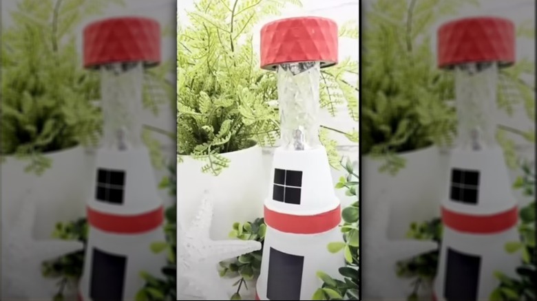 The completed solar lighthouse on a table surrounded by ferns