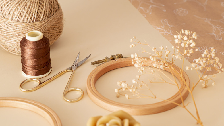 An empty embroidery hoop is surrounded by crafting supplies.