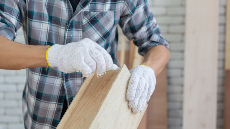 Someone applying glue to a piece of wood