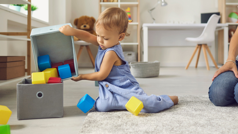 toddler dumping toys in bin