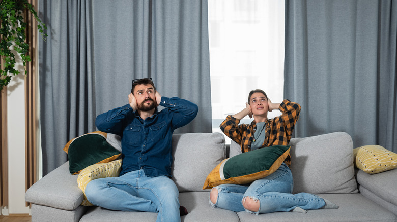 Couple covering ears on couch