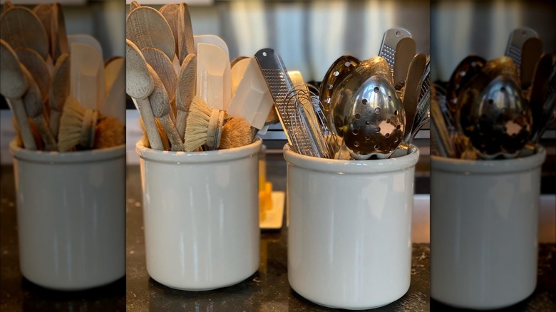 Two white ceramic crocks hold kitchen utensils