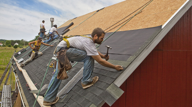 A team of men install watreproofing material and shingles