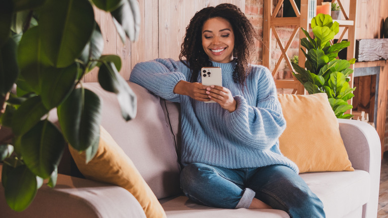 Woman looking at phone in room with plants