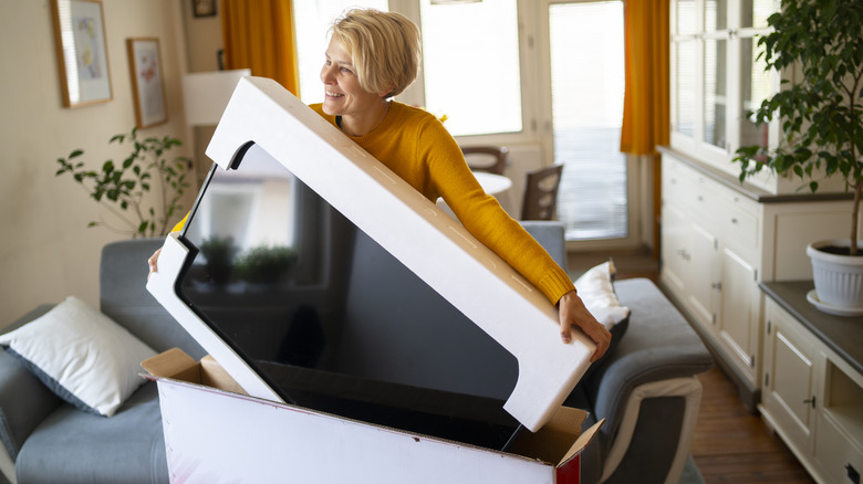 smiling woman unboxing new tv