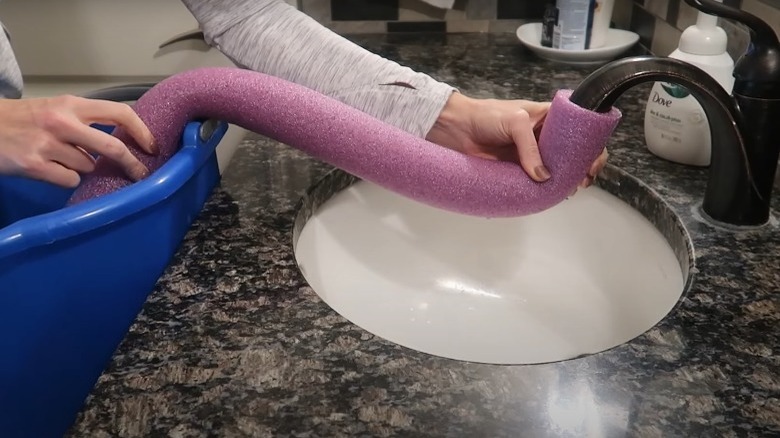 filling bucket from faucet with noodle