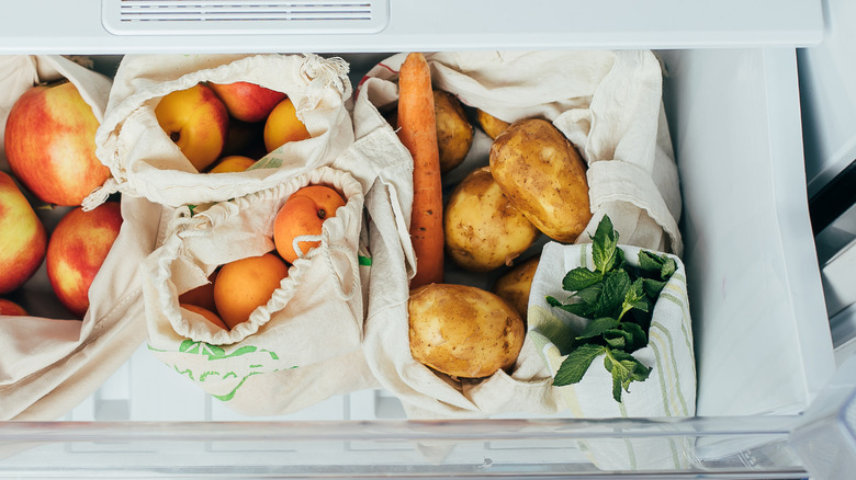 Potatoes and other vegetables and fruits stored in bags in a refrigerator's crisper drawer