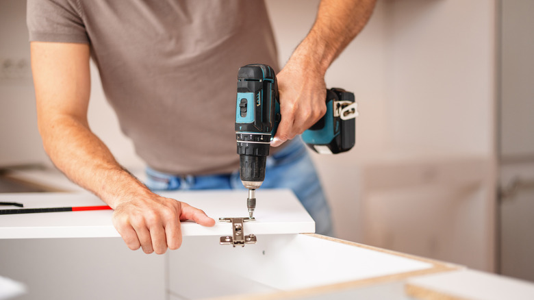 Man adding hinges to cabinet door