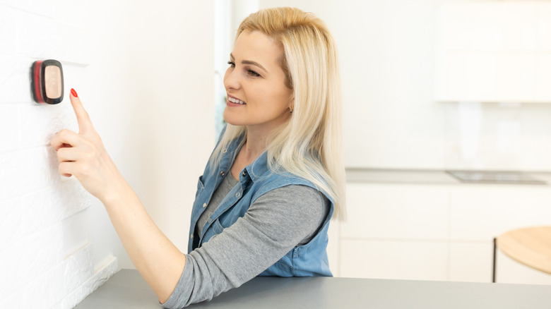 A woman adjusting her thermostat