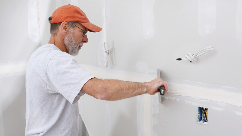 A man installing drywall