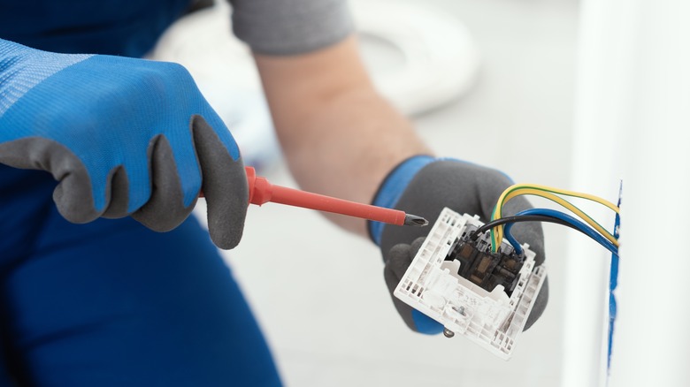 Hands working on electrical fixture