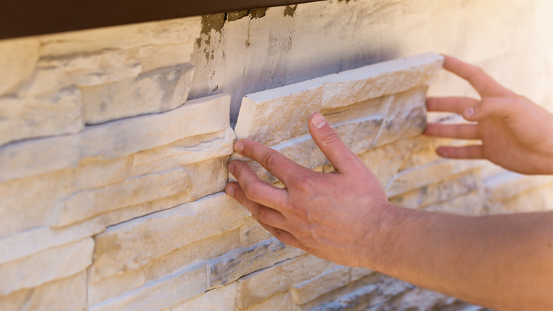 Hands installing stone veneer