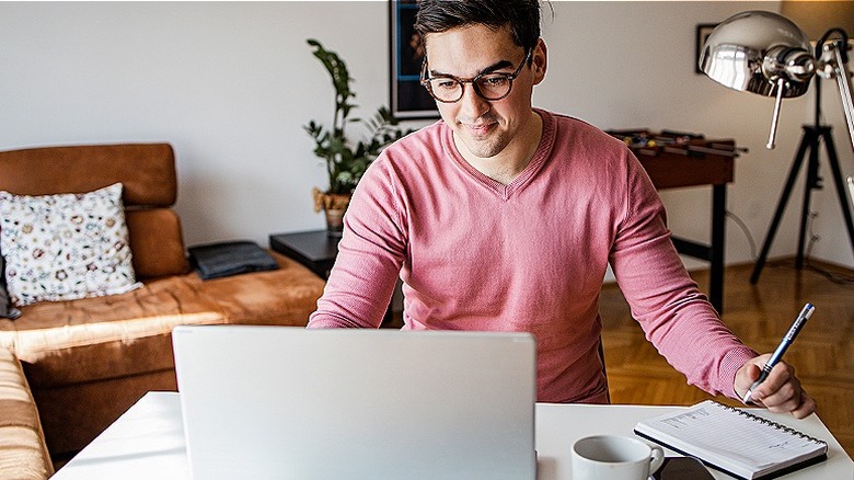 Person making notes from computer