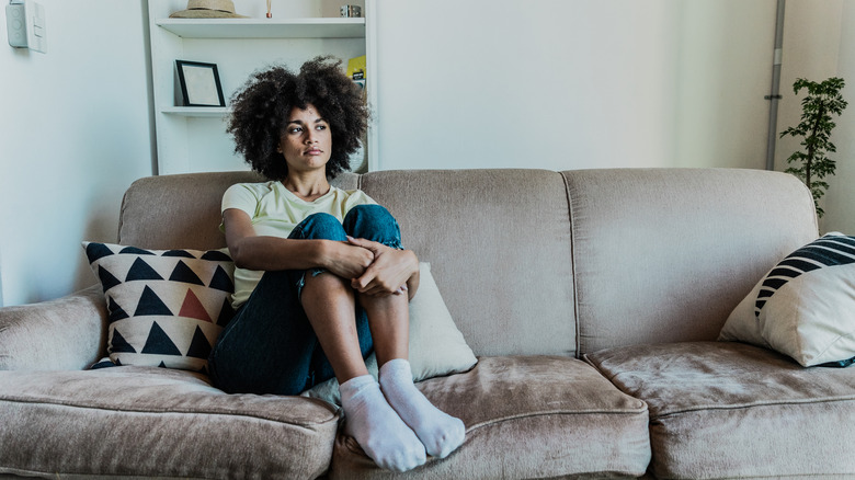 Bored-looking woman sitting on a brown gray sofa