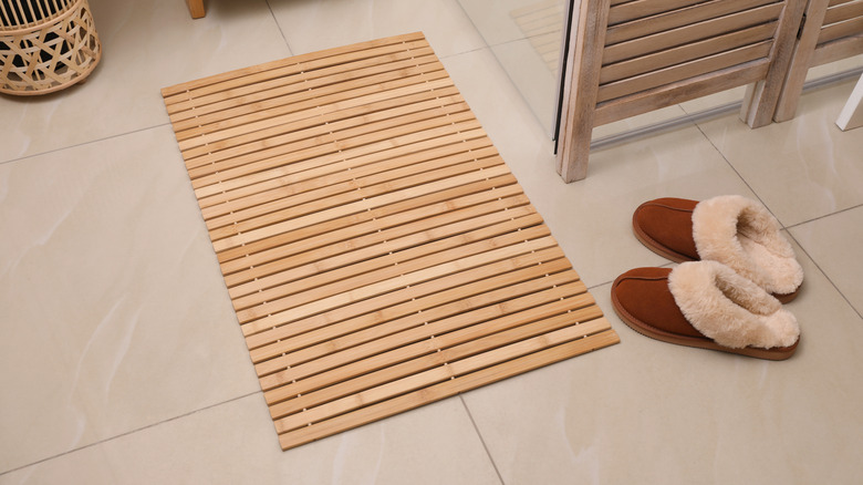 Bamboo bath mat on floor next to brown slippers