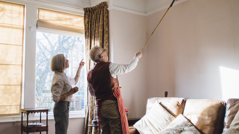 Couple cleaning molding with duster