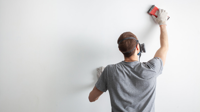 Person sanding a wall