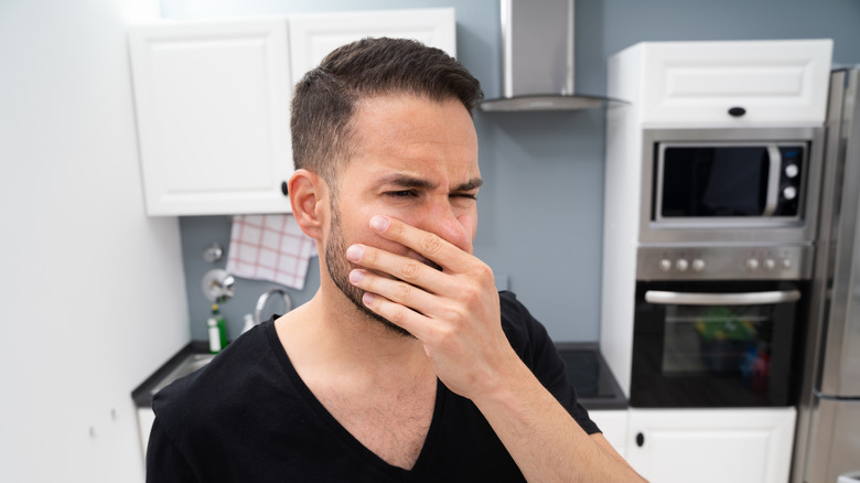 Man covering nose in kitchen