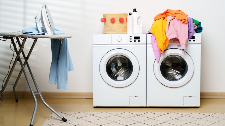 washing machine and dryer, clothes, iron, ironing board and cleaning supplies in laundry room