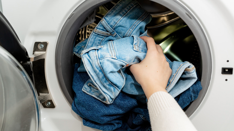 person placing jeans in washing machine