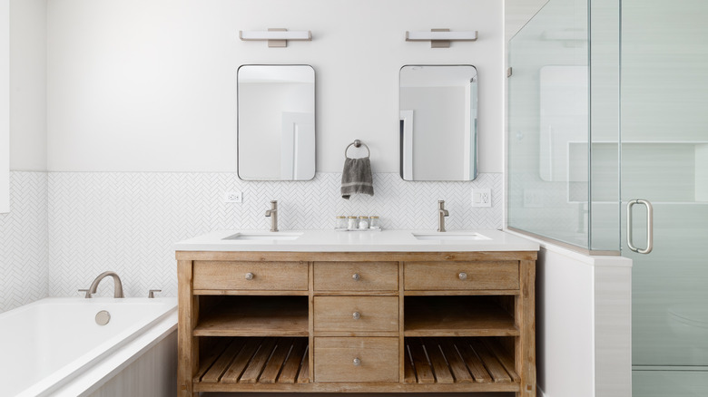 An modern bathroom with a wood vanity and crisp white walls