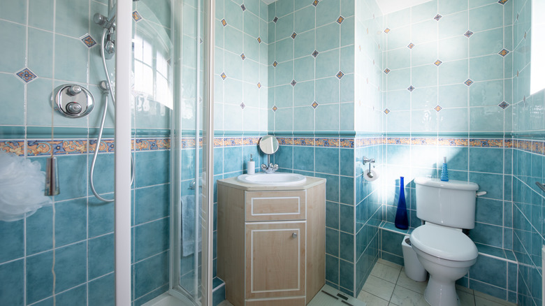 Outdated bathroom will blue tile and a peach sink