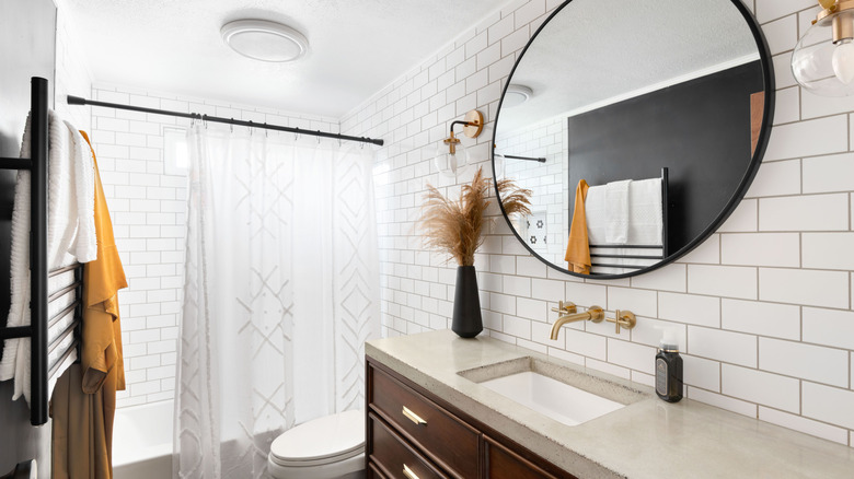 A modern bathroom is fitted with a large mirror and wood cabinets