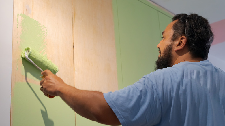 person painting cabinet with roller