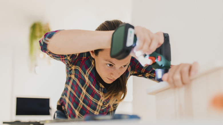 A woman using a heat gun on wood