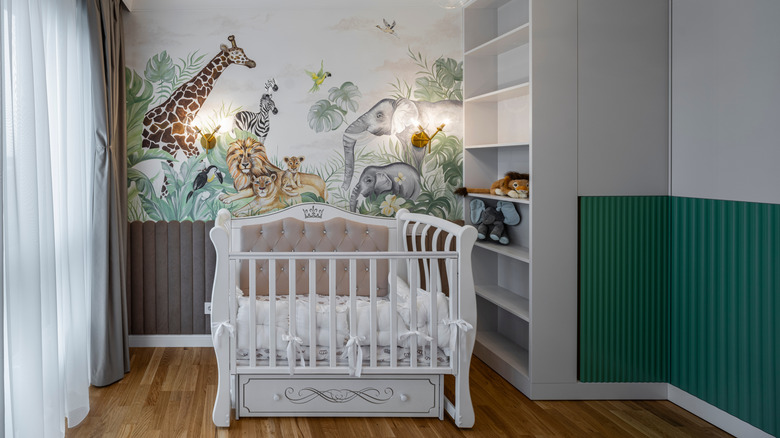 A white crib in front of a safari mural