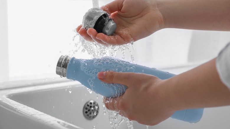 Person handwashing a water bottle