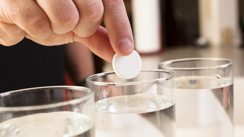 Man drops Alka-Seltzer tablet into glass