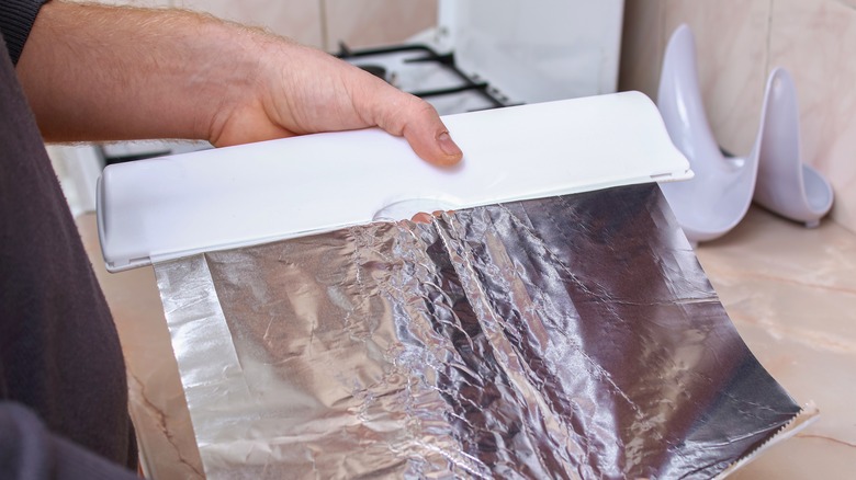 person holding aluminum foil dispenser 