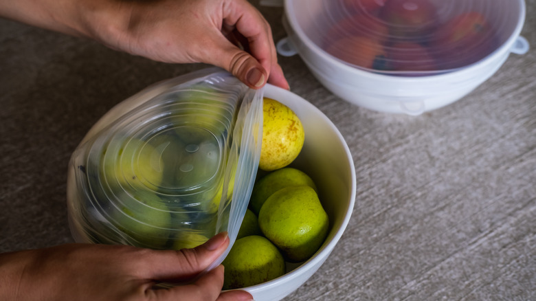 Hands sealing bowl of fruit