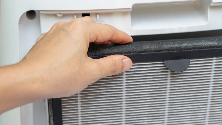 A persons hand is shown removing a dirty HEPA filter