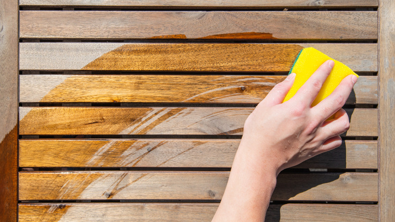 Person cleaning a wood fence using a sponge