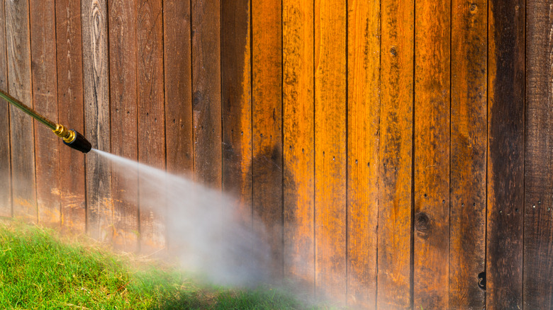 cleaning a fence with a pressure washer to make it like new