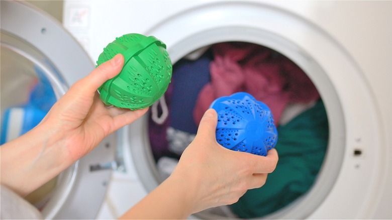 Hands holding reusable laundry balls before placing them inside the washing machine