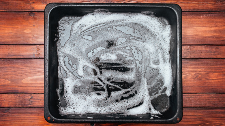 White soapy foam on a black baking sheet