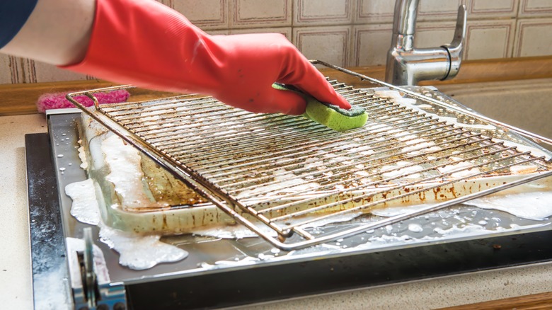 gloved hand cleans oven rack